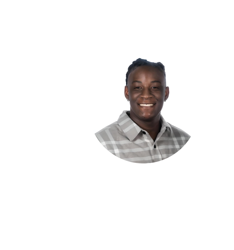 Headshot of a person smiling, wearing a gray plaid shirt, with short braided hair, set against a white background with faint circular patterns on the left side—reflecting the spirit of educational enrichment.